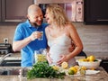 Portrait of smiling laughing white Caucasian couple two people pregnant woman with husband cooking food, drinking citrus juice Royalty Free Stock Photo