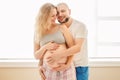 Portrait of smiling laughing white Caucasian young middle age couple, pregnant woman with husband in room hugging cuddling