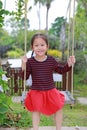 Portrait of smiling little Asian child girl play and sitting on the swing in the nature park Royalty Free Stock Photo