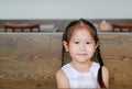 Portrait of smiling little Asian child girl sitting on the wood table with looking camera Royalty Free Stock Photo