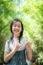 Portrait of smiling little asian girl right sign language meaning I Love You and look at the camera on bamboo forest,green nature Royalty Free Stock Photo