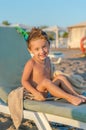 Portrait smiling little baby boy sitting near the sea, ocean. Positive human emotions, feelings, joy. Funny cute child making vaca