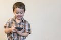 Portrait of a smiling little boy holding mobile phone isolated over light background. cute kid playing games on smartphone. copy Royalty Free Stock Photo