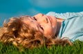 Portrait of a smiling little boy lying on green grass and dreaming. Cute child enjoying nature outdoors. Healthy Royalty Free Stock Photo