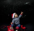 Portrait of smiling little boy wearing christmas hat near red vintage telephone sitting on black background Royalty Free Stock Photo