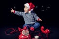 Portrait of smiling little boy wearing christmas hat near red vintage telephone sitting on black background Royalty Free Stock Photo