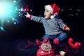 Portrait of smiling little boy wearing christmas hat near red vintage telephone sitting on black background Royalty Free Stock Photo