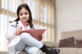 Portrait of smiling little child dressed in doctor`s uniform handwriting a report