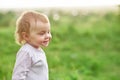 Portrait of smiling little child walking on green field.