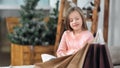 Portrait of smiling little cute girl posing with Christmas present shopping bag at cosiness home