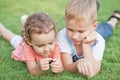 Portrait of a smiling little girl and boy lying on green grass Royalty Free Stock Photo