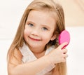Portrait of smiling little girl brushing her hair Royalty Free Stock Photo