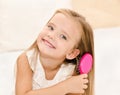 Portrait of smiling little girl brushing her hair Royalty Free Stock Photo