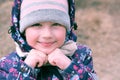 Portrait of smiling little girl with knit hat and scarf. Winter or autumn outdoors kids activity