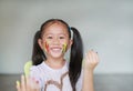 Portrait of smiling little girl looking through her colorful hands and cheek painted in kids room. Focus at baby face Royalty Free Stock Photo