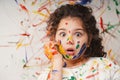 Portrait of smiling little girl looking through her colorful hands and cheek  painted in kids room Royalty Free Stock Photo