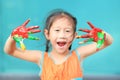 Portrait of smiling little girl looking through her colorful hands painted. Focus at baby hands Royalty Free Stock Photo