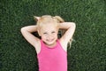 Portrait of a smiling little girl lying on green grass Royalty Free Stock Photo