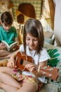 Portrait of smiling little girl playing ukulele while boy reading book on handmade teepee at home Royalty Free Stock Photo