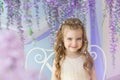 Portrait of smiling little girl in a yellow dress in a room decorated a lilacs Royalty Free Stock Photo
