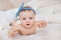 Portrait of smiling little infant with a blue diadem plays on a bed