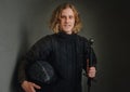 Portrait of a smiling long-haired young teen dressed in black historical fencing armor with a long medieval sharp sword Royalty Free Stock Photo