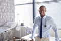 Portrait Of Smiling Male Doctor With Stethoscope Standing By Desk In Office Royalty Free Stock Photo