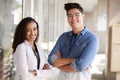 Portrait Of Smiling Male And Female School Teachers Standing In Corridor Of College Building