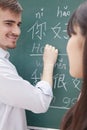 Portrait of smiling male teacher with student in front of chalkboard writing