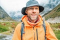 Portrait of smiling Man with backpack dressed orange waterproof jacket and funny hat walking the path during Makalu Barun National