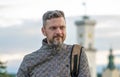 Portrait of a smiling man with a beard of 35-40 years old with a backpack on his shoulder against a blurry background of old archi Royalty Free Stock Photo