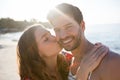 Portrait of smiling man being kissed by his girlfriend at beach