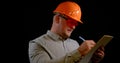 Portrait of a smiling man on a black background in the studio, he is wearing an orange construction helmet, safety Royalty Free Stock Photo