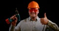 Portrait of a smiling man on a black background, he is wearing an construction helmet, safety glasses and a shirt, he is Royalty Free Stock Photo