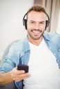 Portrait of smiling man listening to music while holding mobile phone Royalty Free Stock Photo