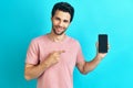 Portrait of smiling man pointing to mobile phone on blue background Royalty Free Stock Photo