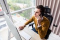 Portrait of smiling businessman speaking on mobile phone, sitting at desk, looking at computer screen Royalty Free Stock Photo