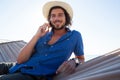 Portrait of smiling man talking on mobile phone while relaxing at beach Royalty Free Stock Photo