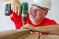 Cheerful worker assembling wood with drill-drive Royalty Free Stock Photo