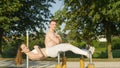 PORTRAIT: Smiling man and woman looking into camera while doing sit ups in park. Royalty Free Stock Photo