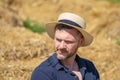 Portrait of a smiling man 35-40 years old with a beard in a straw hat on a field with hay. Concept: farming and agriculture, summe Royalty Free Stock Photo