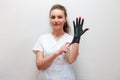 Portrait of a smiling manicurist woman wearing latex black glove with pink nailpolish. The concept of professional care Royalty Free Stock Photo