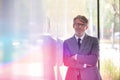 Portrait of smiling mature businessman with arms crossed leaning on wall at office Royalty Free Stock Photo