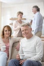 Portrait of smiling mature couple holding coffee while sitting against friends at home Royalty Free Stock Photo