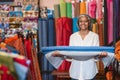 Smiling mature woman holding cloth rolls in her fabric shop Royalty Free Stock Photo