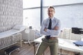 Portrait Of Smiling Mature Male Doctor With Stethoscope Standing By Desk In Office Royalty Free Stock Photo