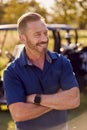 Portrait Of Smiling Mature Male Golfer Standing By Buggy On Golf Course Royalty Free Stock Photo