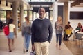 Portrait Of Smiling Mature Male Tutor In Busy University Or College Building With Students Royalty Free Stock Photo