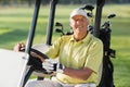 Portrait of smiling mature man driving golf buggy