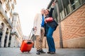 Portrait of smiling mature married couple sightseeing carrying a suitcase for a romantic journey trip while looking for